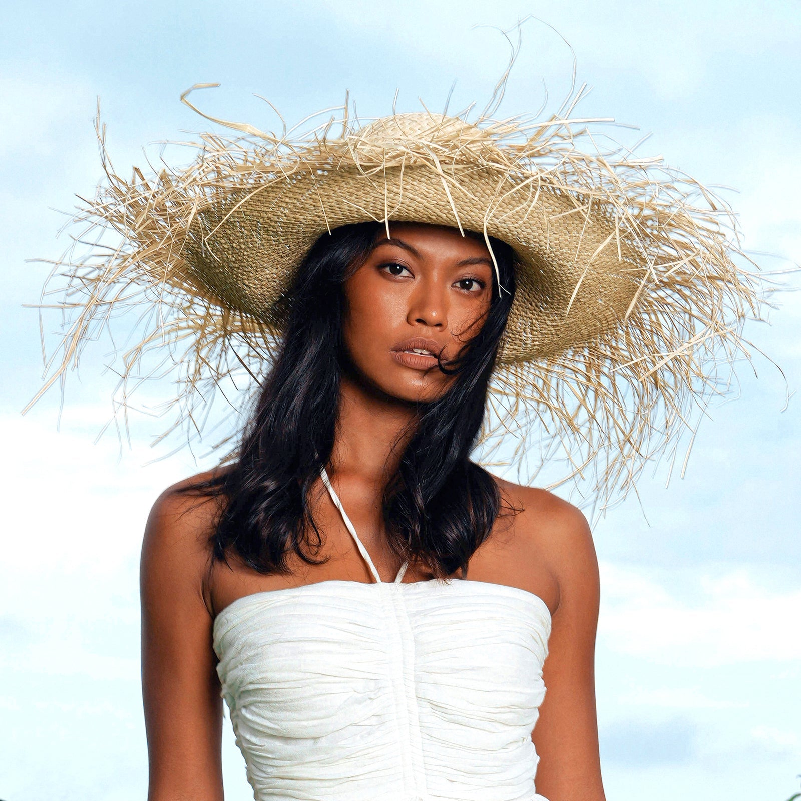 Woman wearing a straw hat against a clear blue sky