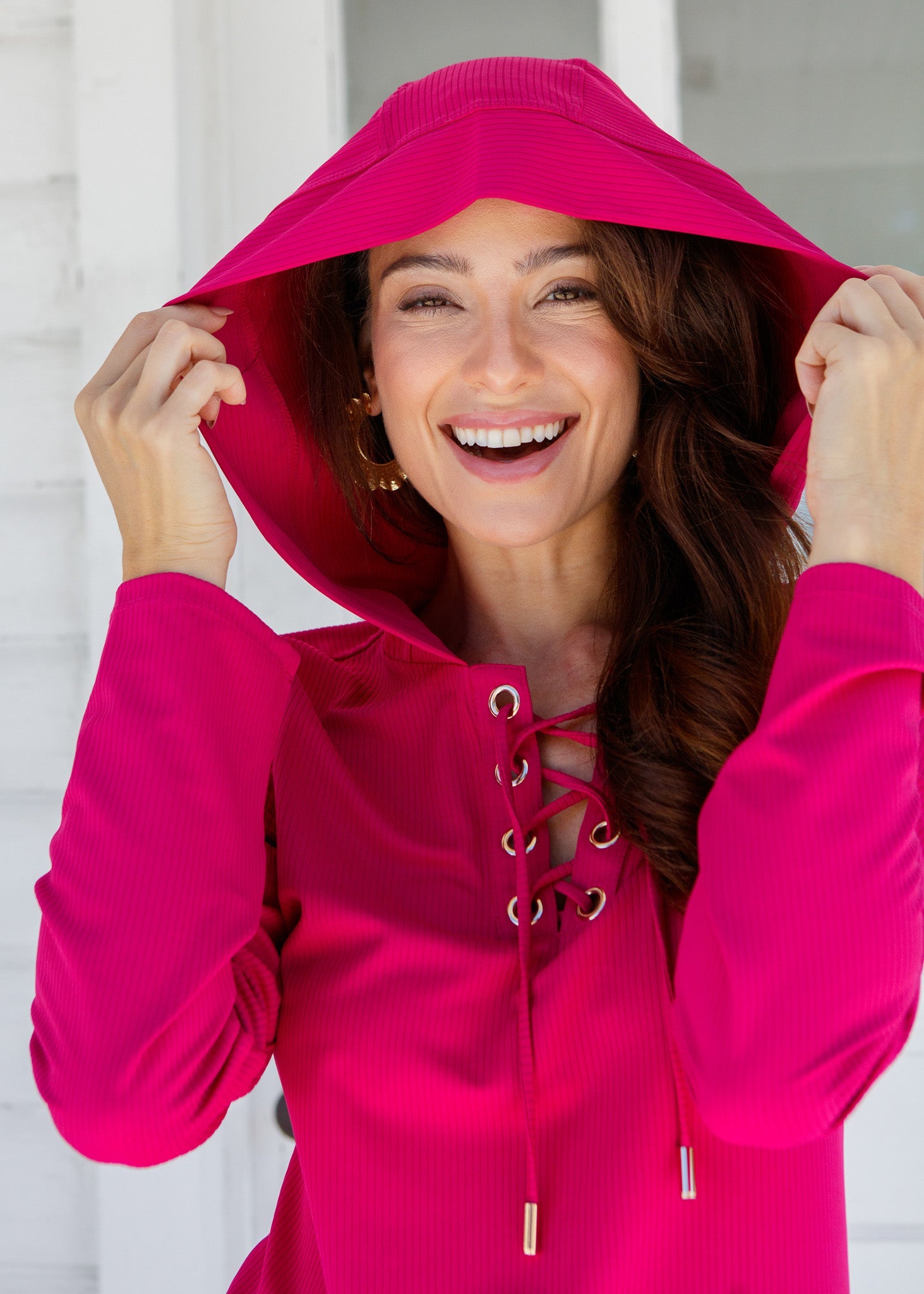 Woman wearing a bright pink hoodie with a white background