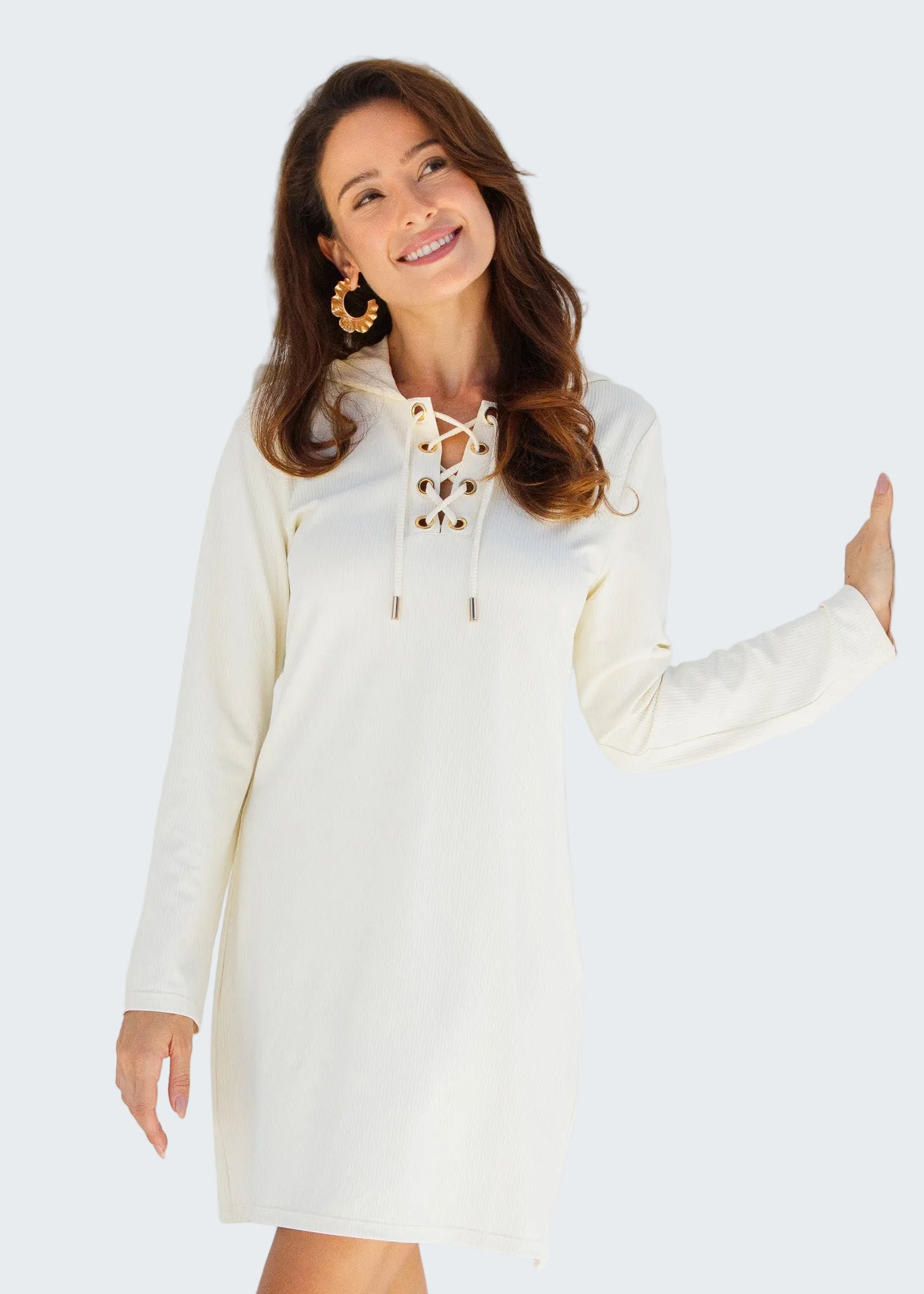 Woman wearing a white lace-up dress standing in front of a white wooden door.