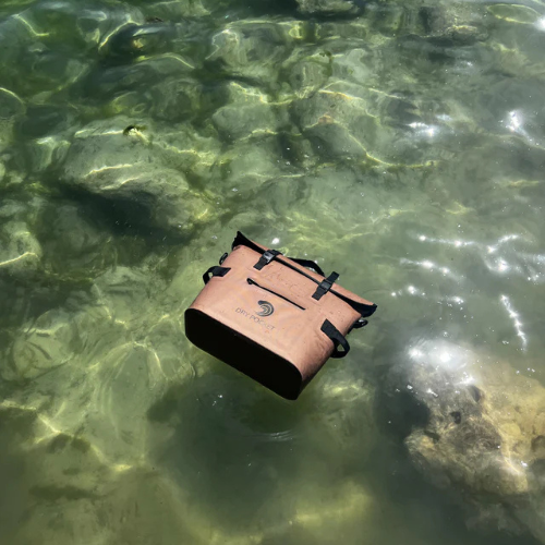 Brown bag floating in clear water with rocks below