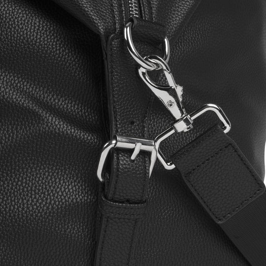 Close-up of a black leather bag with silver hardware on a black background
