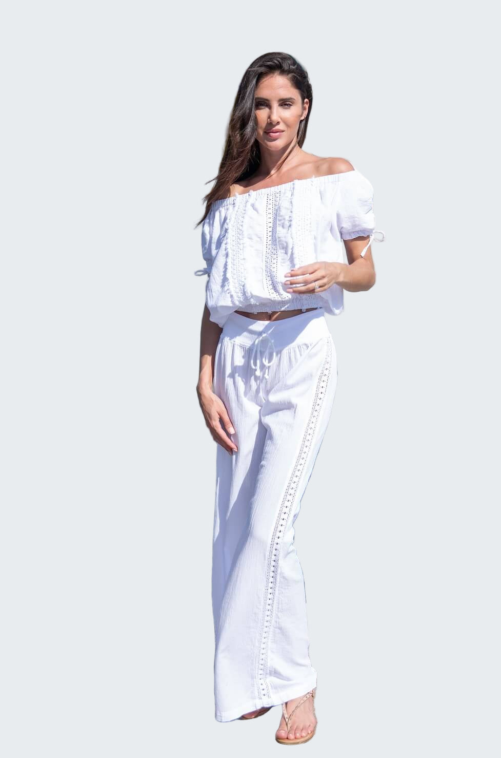 Woman in a white outfit standing by a marina with boats in the background