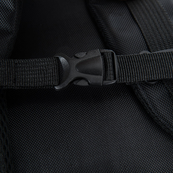 Close-up of a black backpack strap with a buckle on a dark background