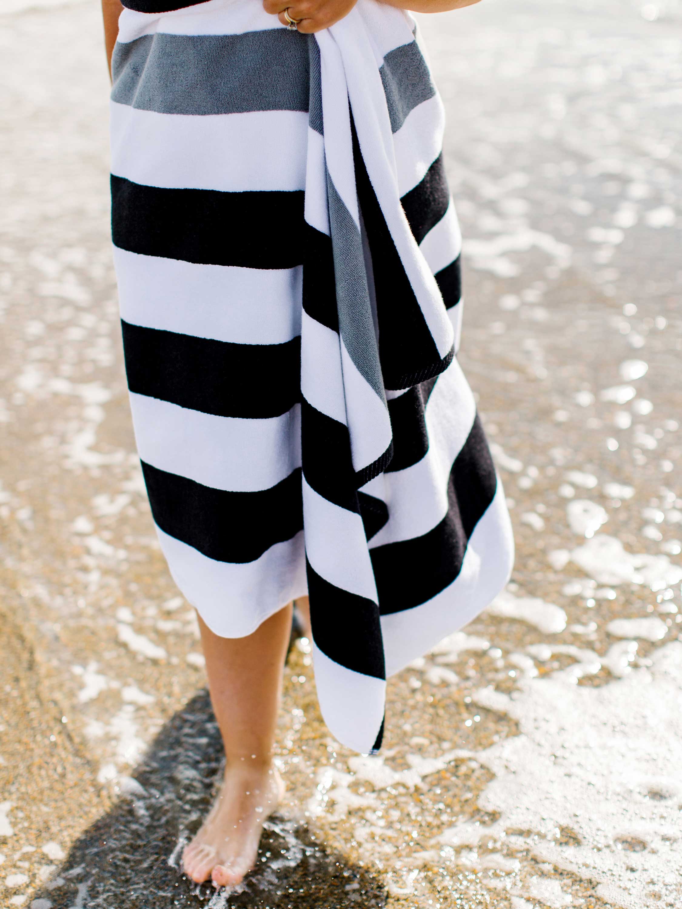 Person on a beach wearing a black and white striped towel.