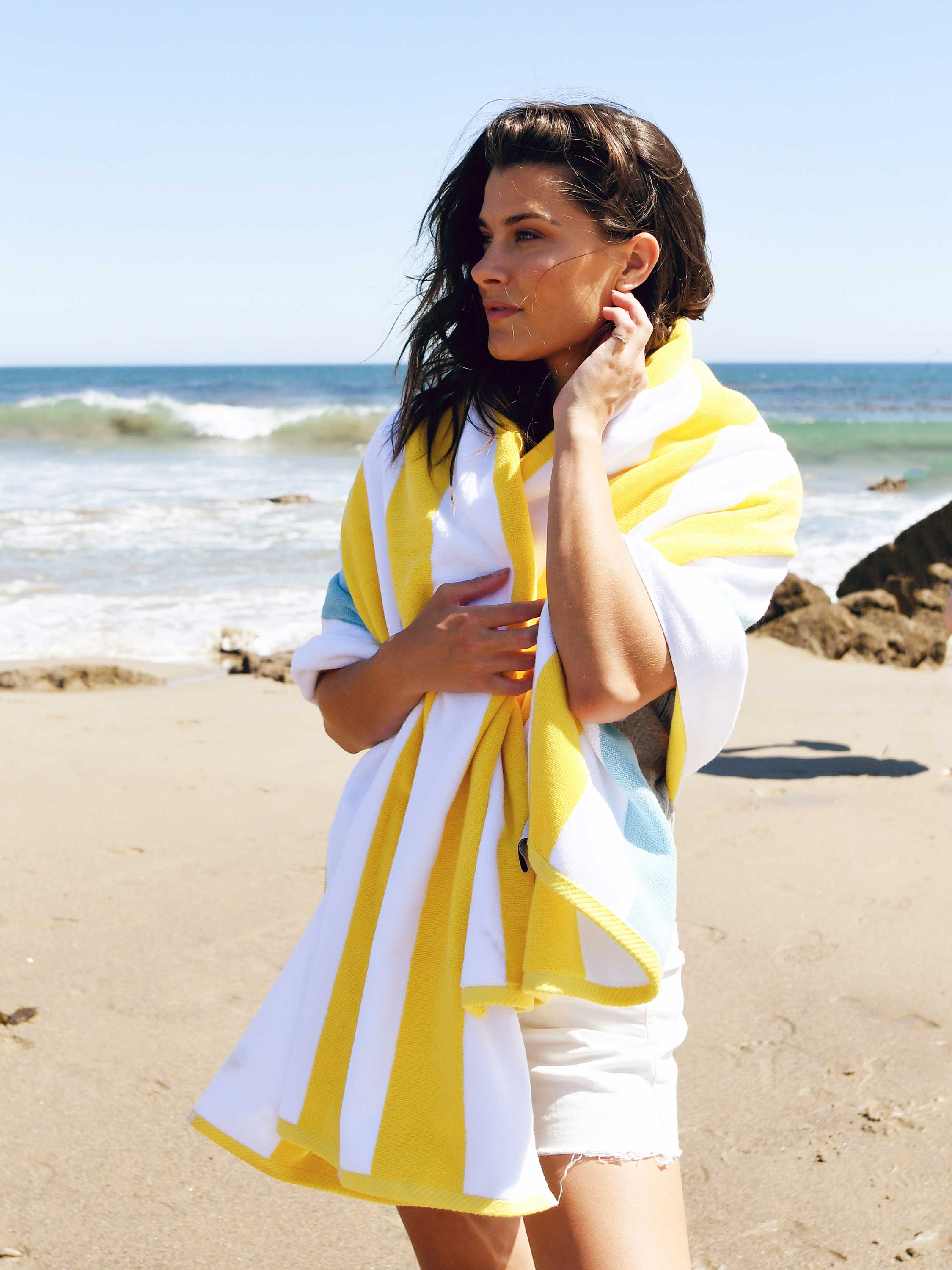 Woman on a beach wearing a yellow and white striped cover-up.