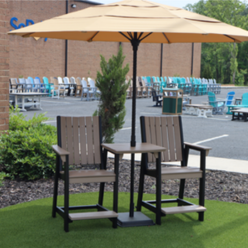 Outdoor patio set with two chairs and a table under an umbrella on a grassy area.