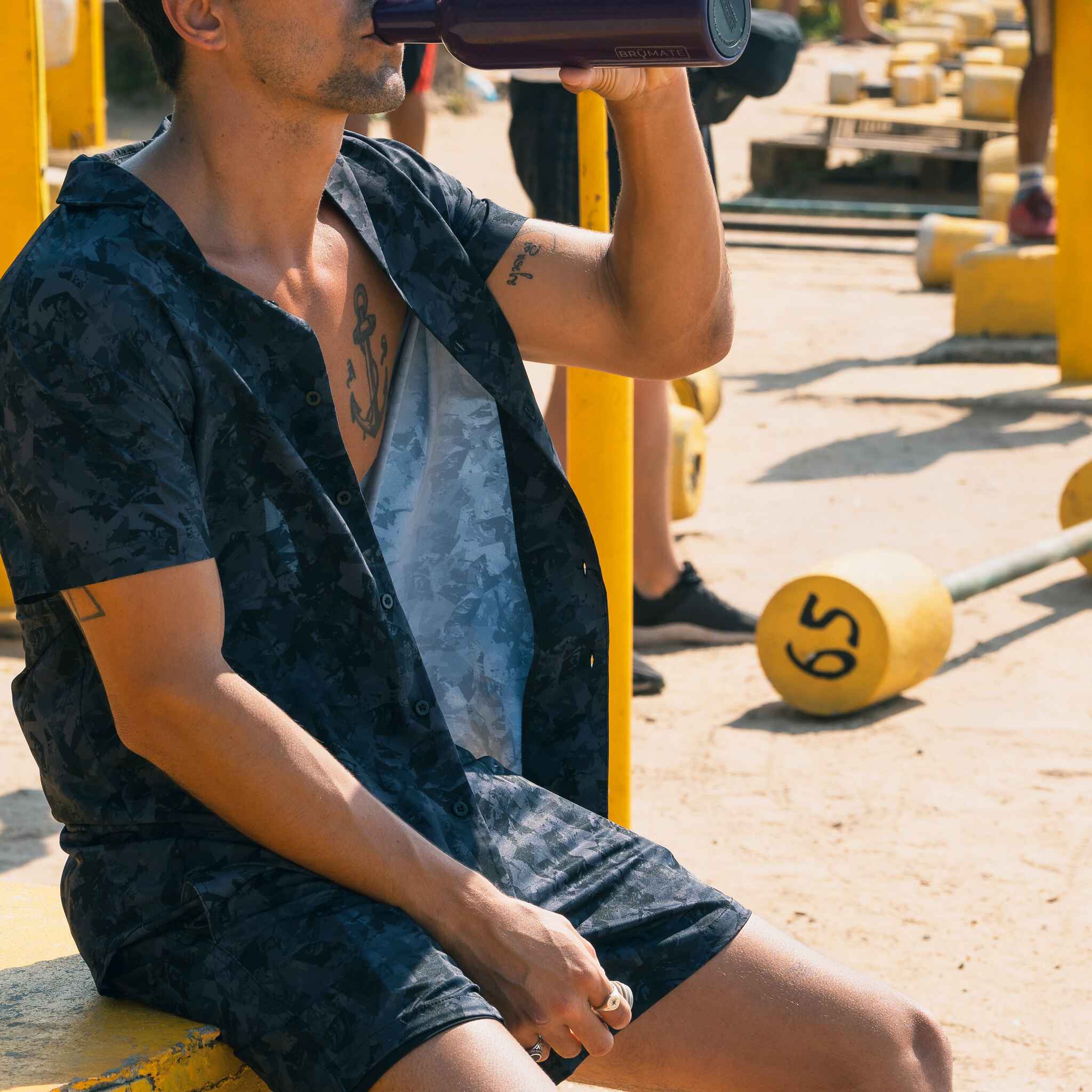 Man sitting on a yellow bench with a barbell over his head in an outdoor setting