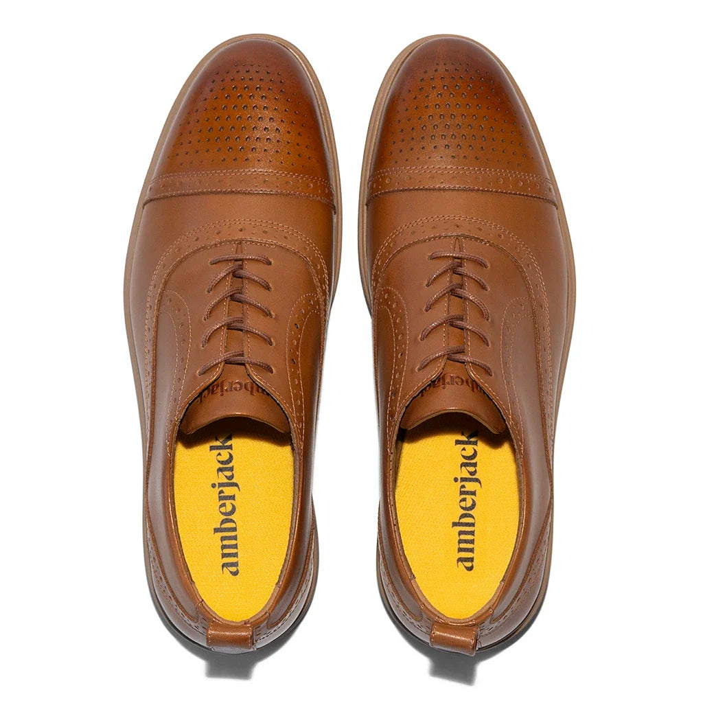 Pair of brown leather shoes with yellow soles on a white background