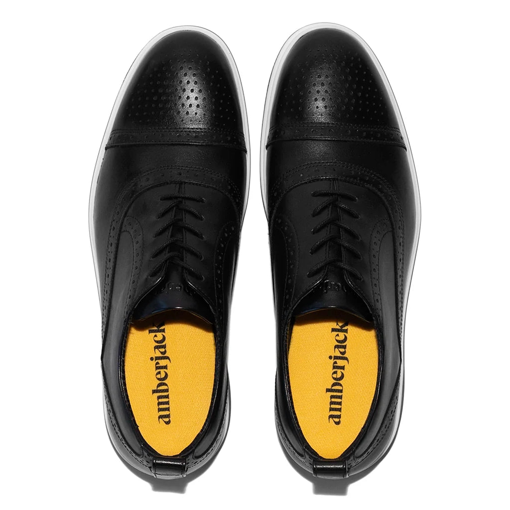 Black leather shoes with yellow soles on a white background