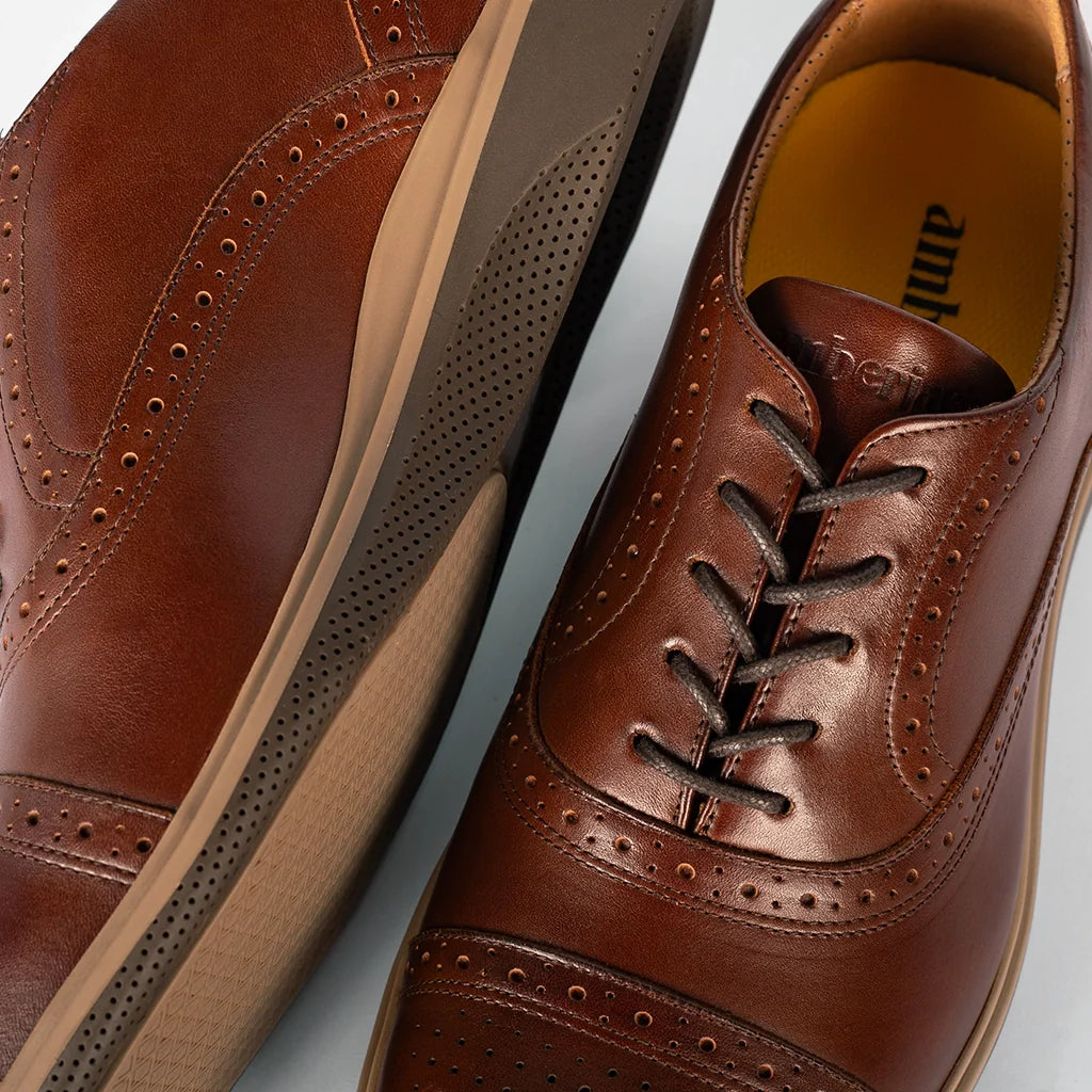 Brown leather dress shoes with laces on a light gray background