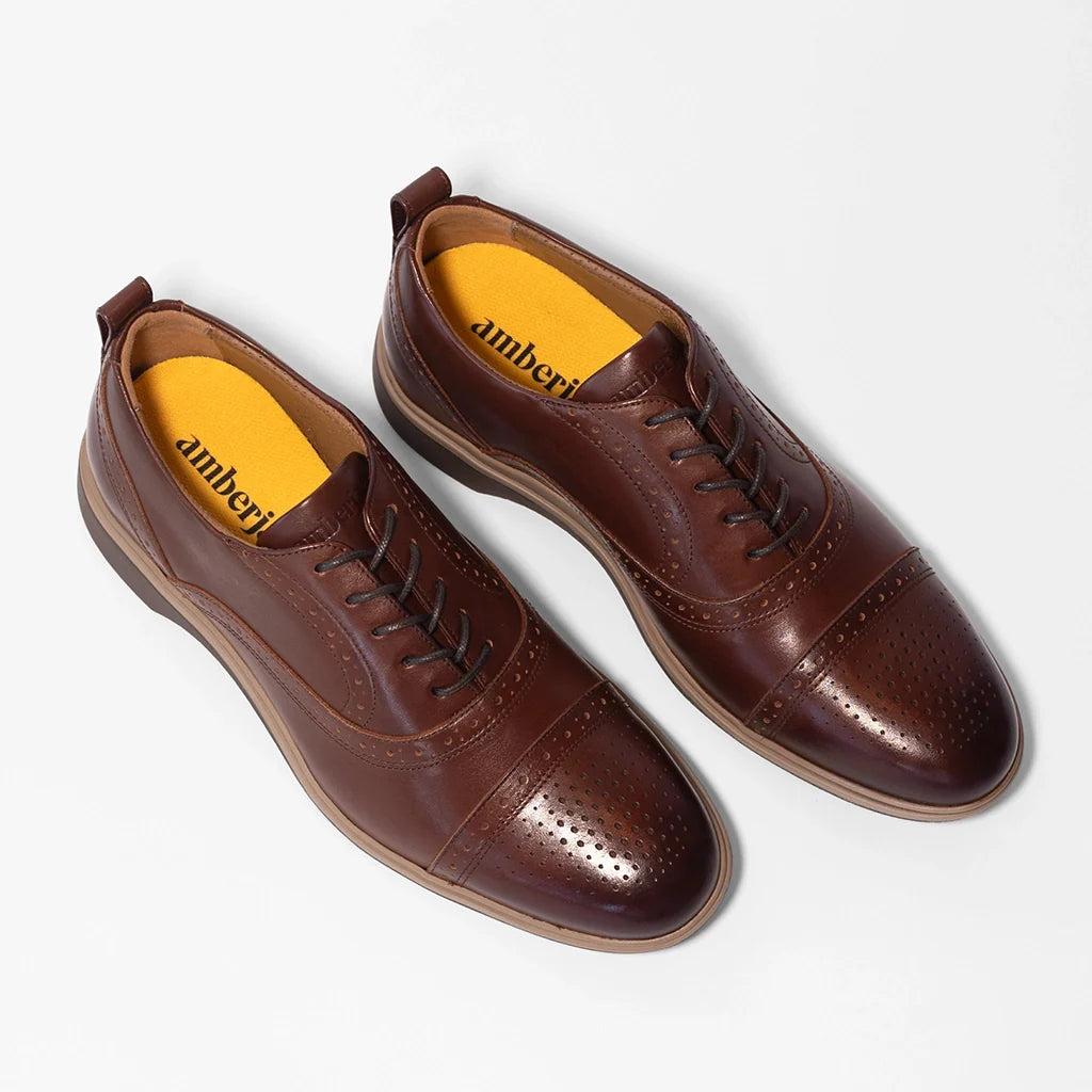 Brown leather shoes with yellow lining on a white background