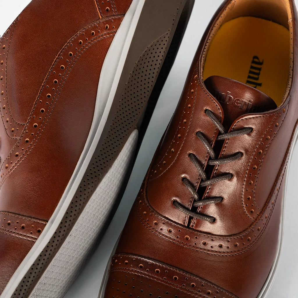 Close-up of brown leather dress shoes with white soles on a light gray background