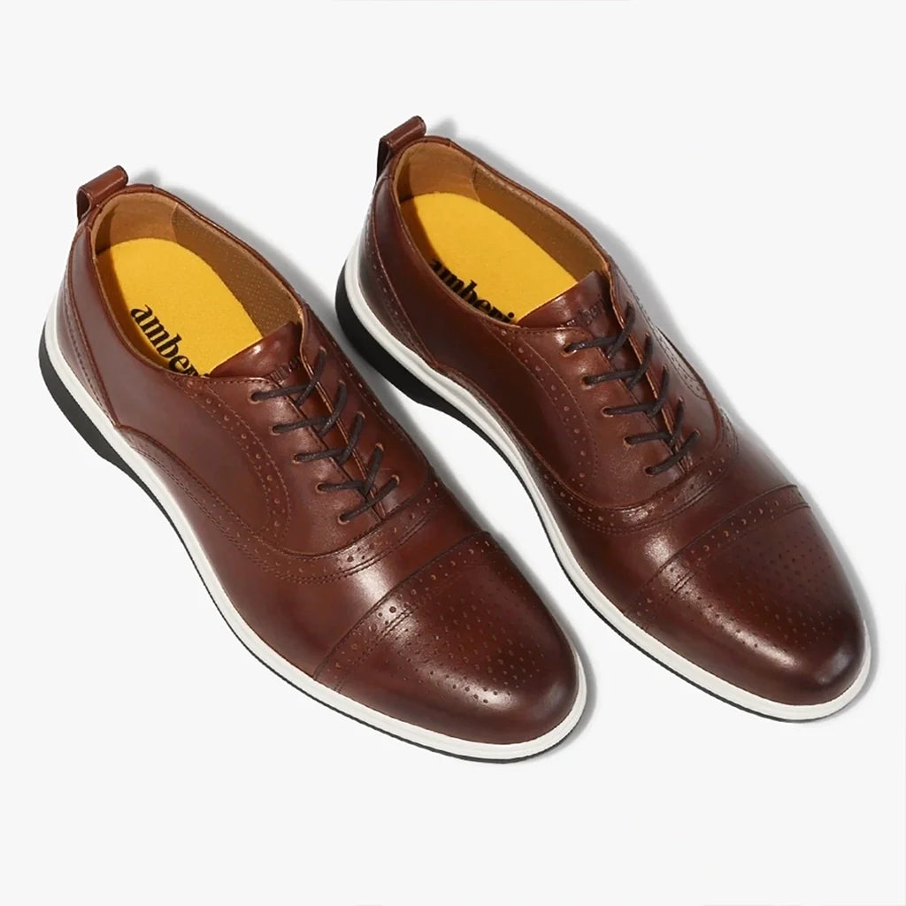 Pair of brown leather shoes with yellow soles on a white background