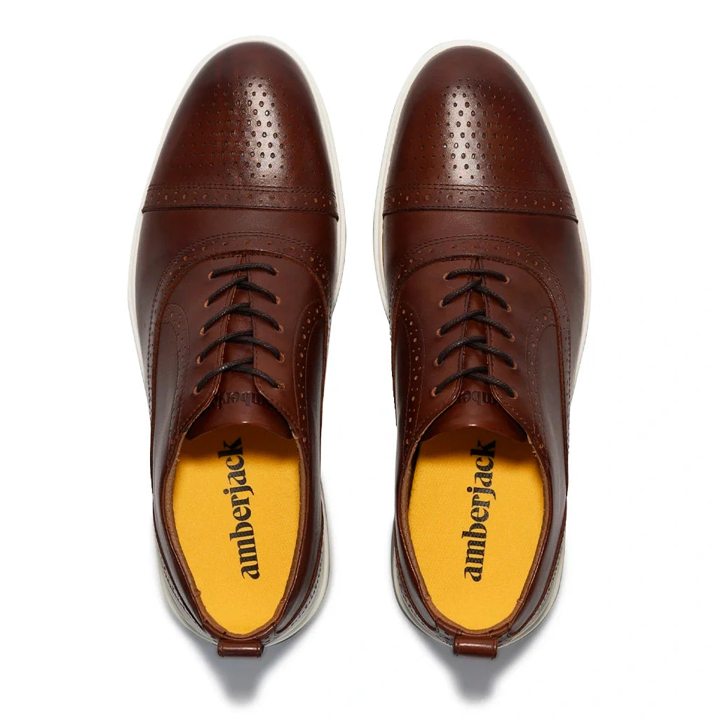 Brown leather shoes with yellow soles on a white background