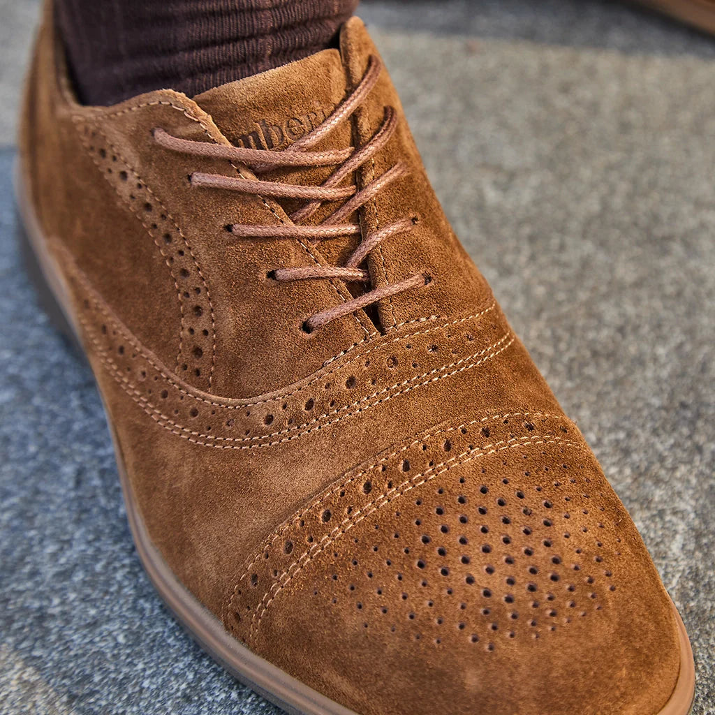 Brown suede shoe with perforated design on a textured surface