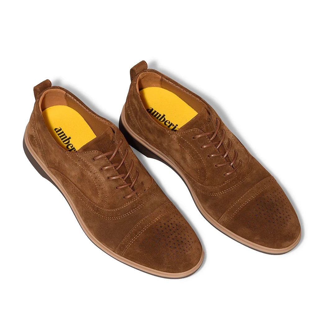 Pair of brown suede shoes with yellow lining on a white background