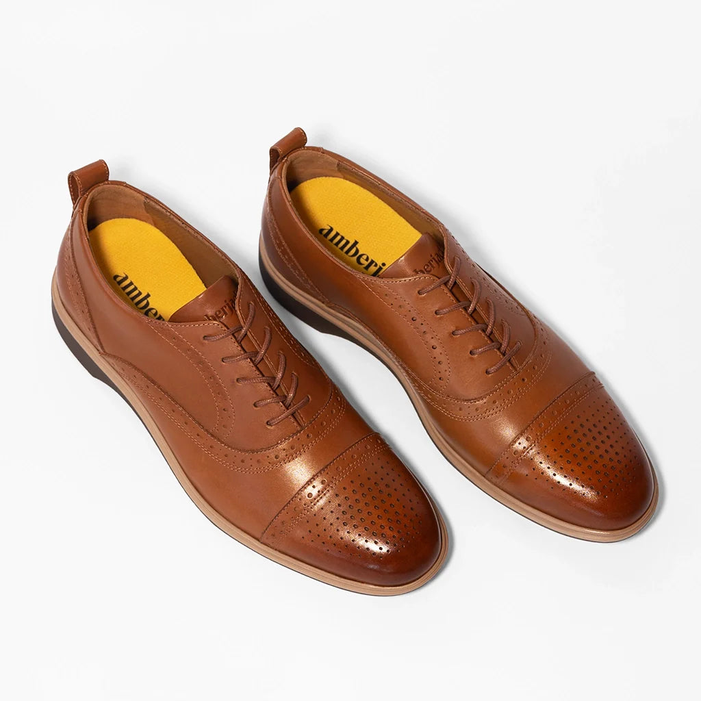 Pair of brown leather shoes with yellow soles on a white background