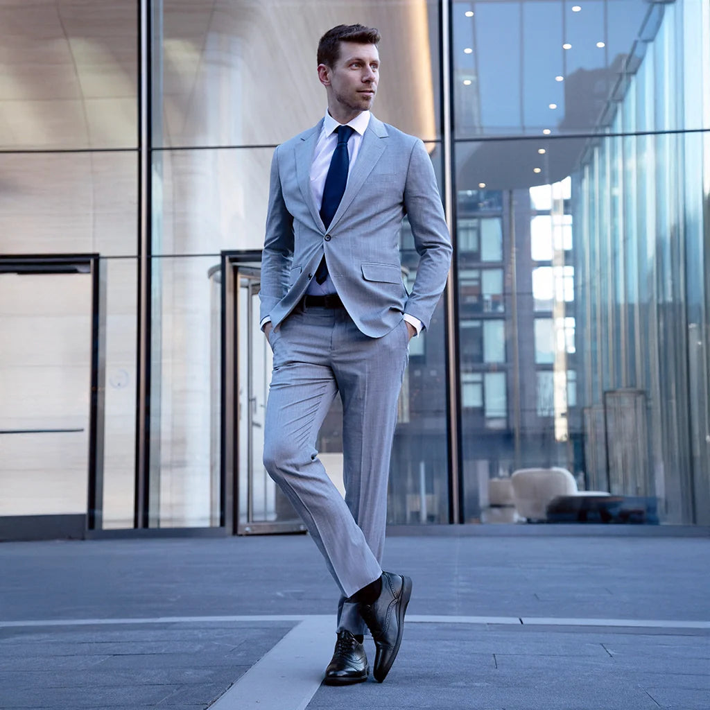 Man in a gray suit standing in front of modern glass buildings