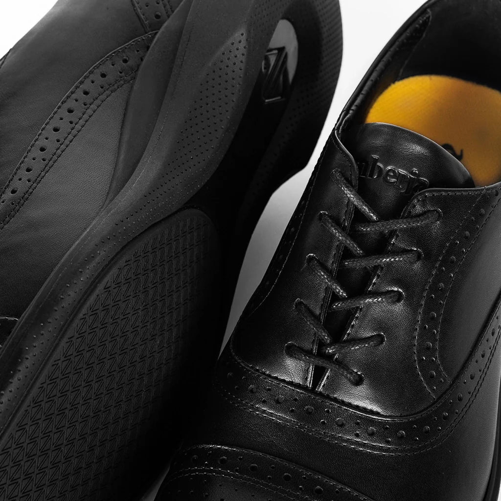 Close-up of a black dress shoe with a yellow sole on a white background