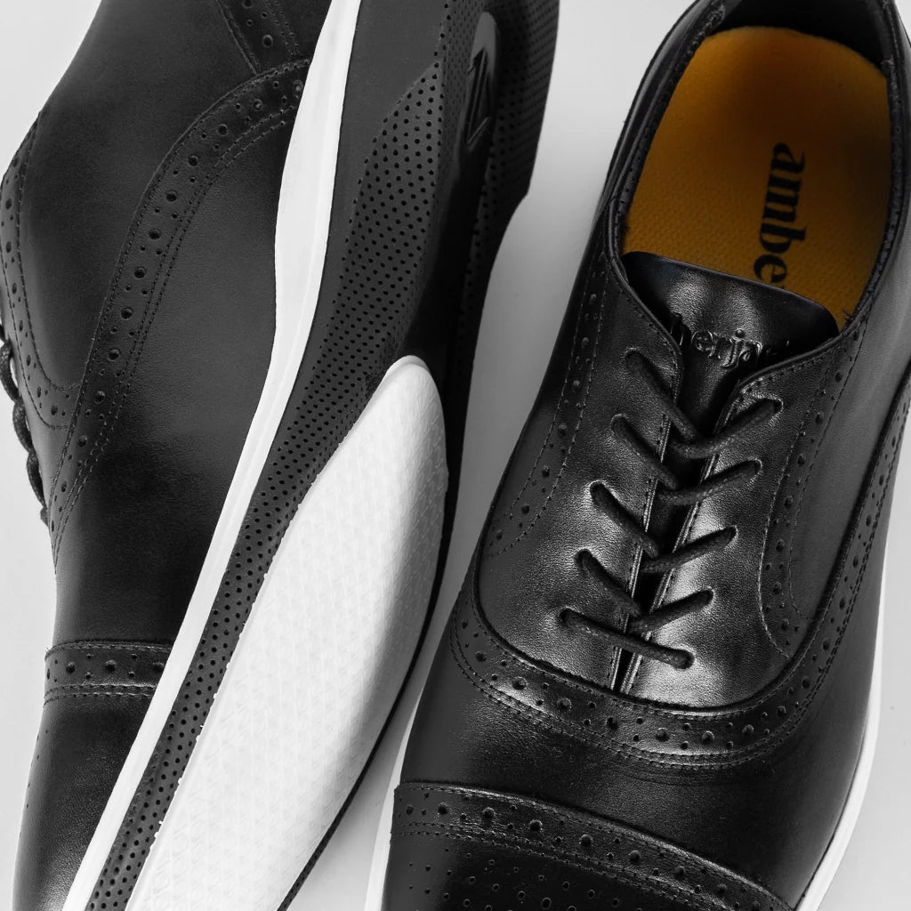 Black leather shoes with white soles on a light gray background