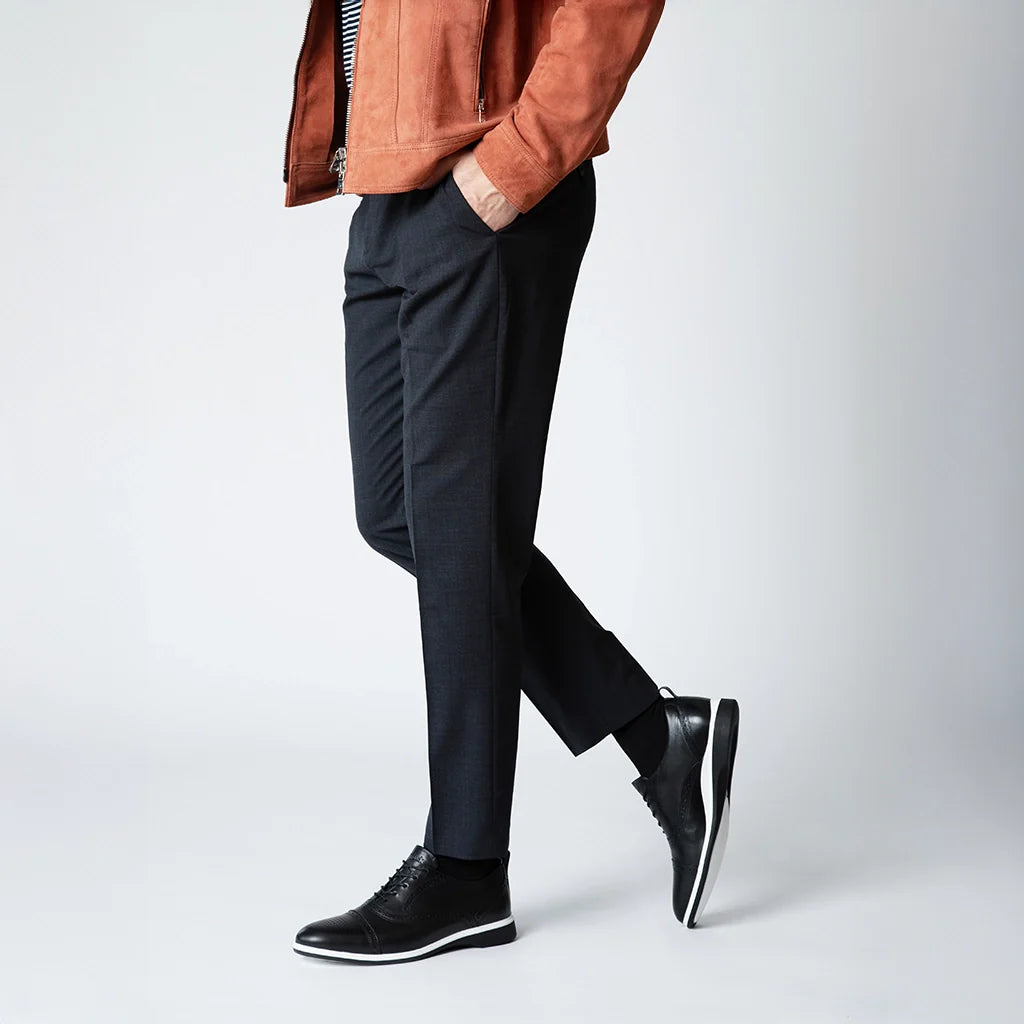 Person wearing black pants and black shoes on a white background