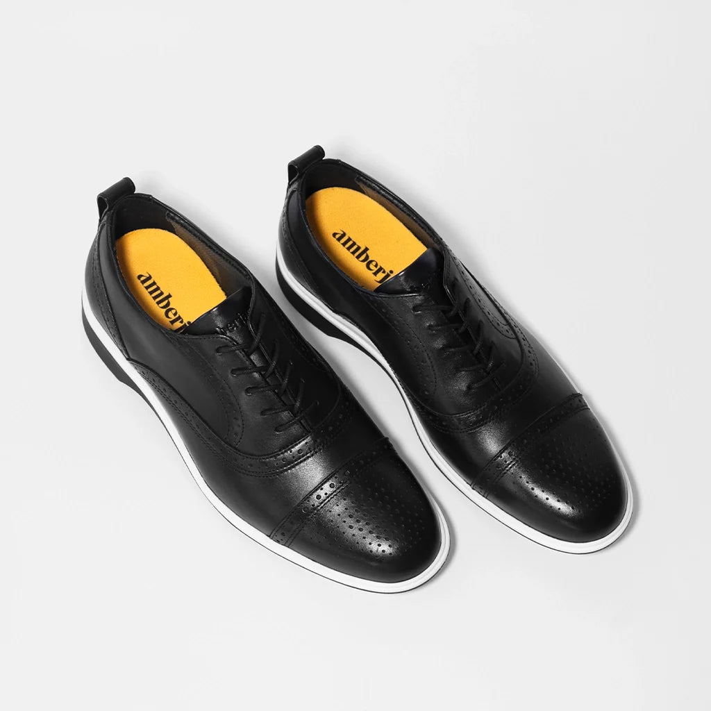Black shoes with yellow soles on a light gray background