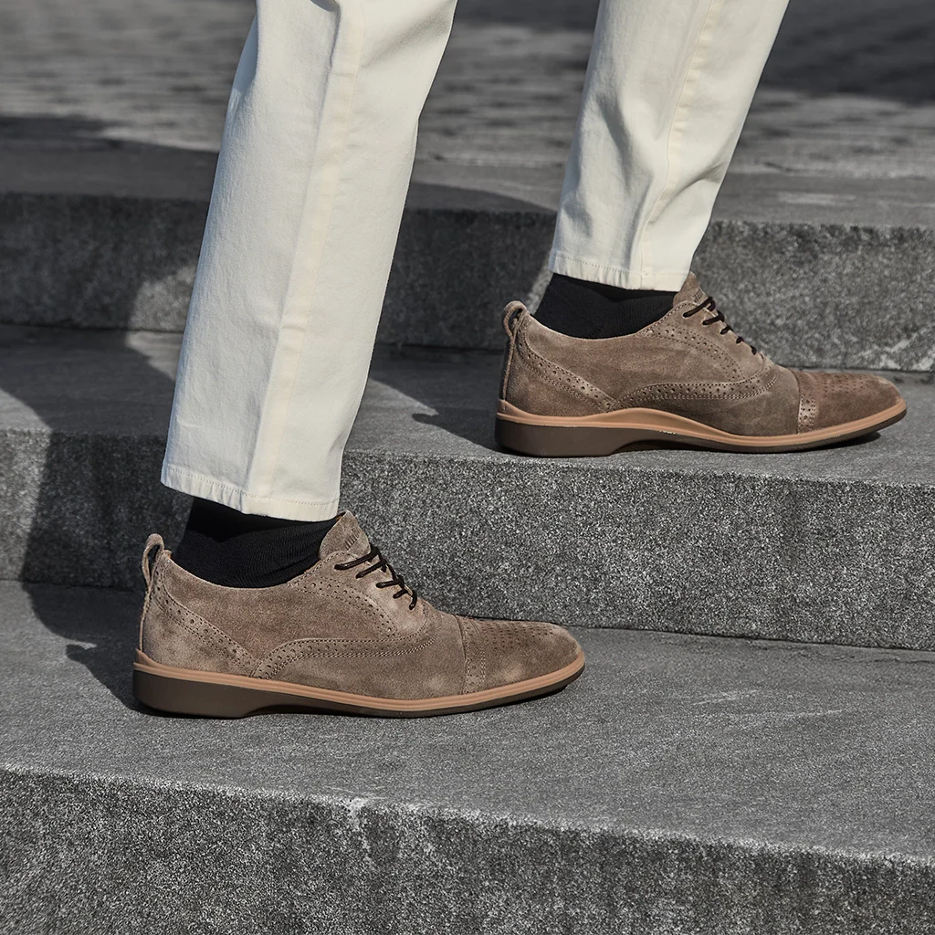 Brown suede shoes worn by a person stepping onto stone steps.