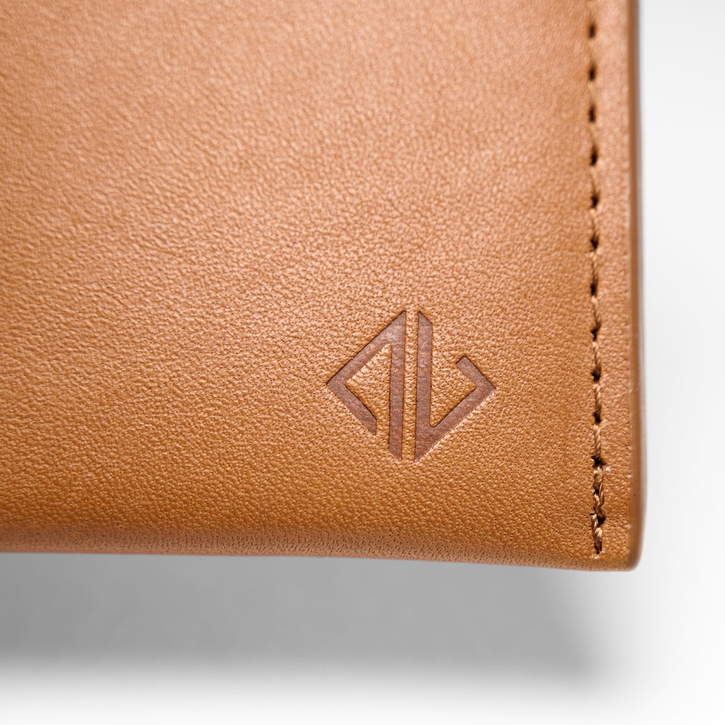 Close-up of a brown leather wallet with a brand logo on a light gray background