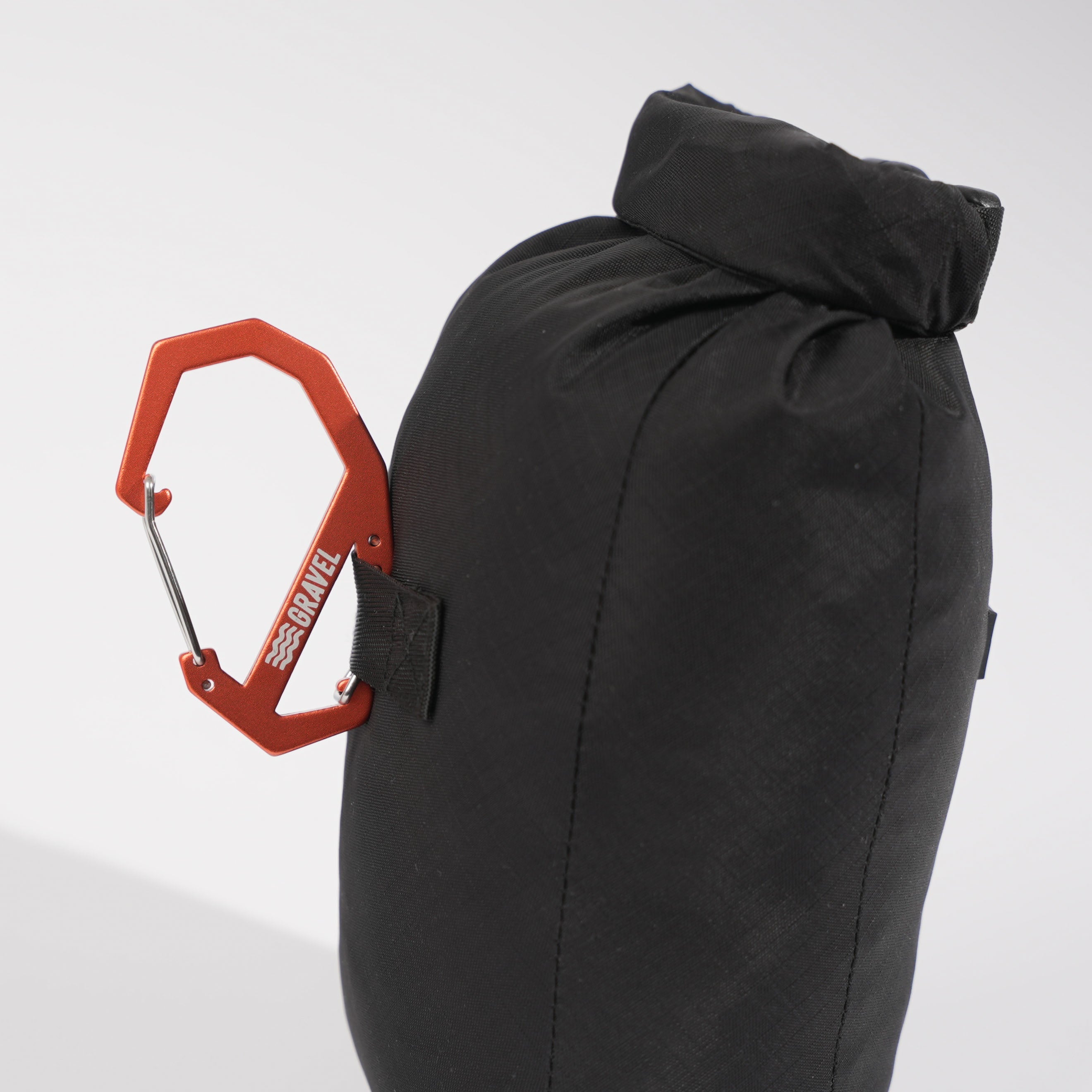 Black sleeping bag with a red carabiner attached on a white background
