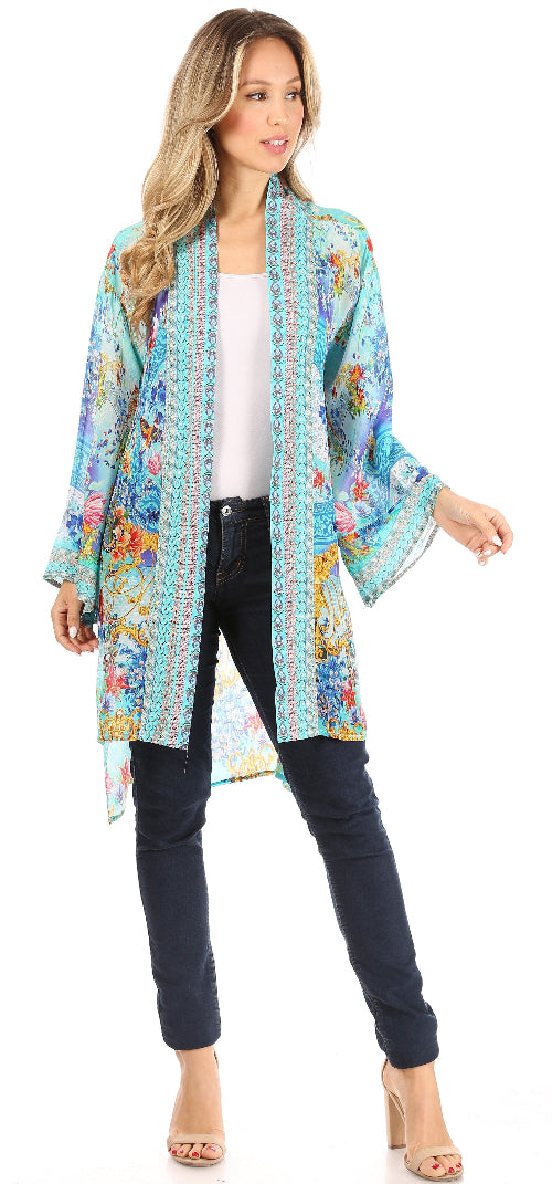 Woman wearing a colorful floral kimono over a white top and black pants on a white background