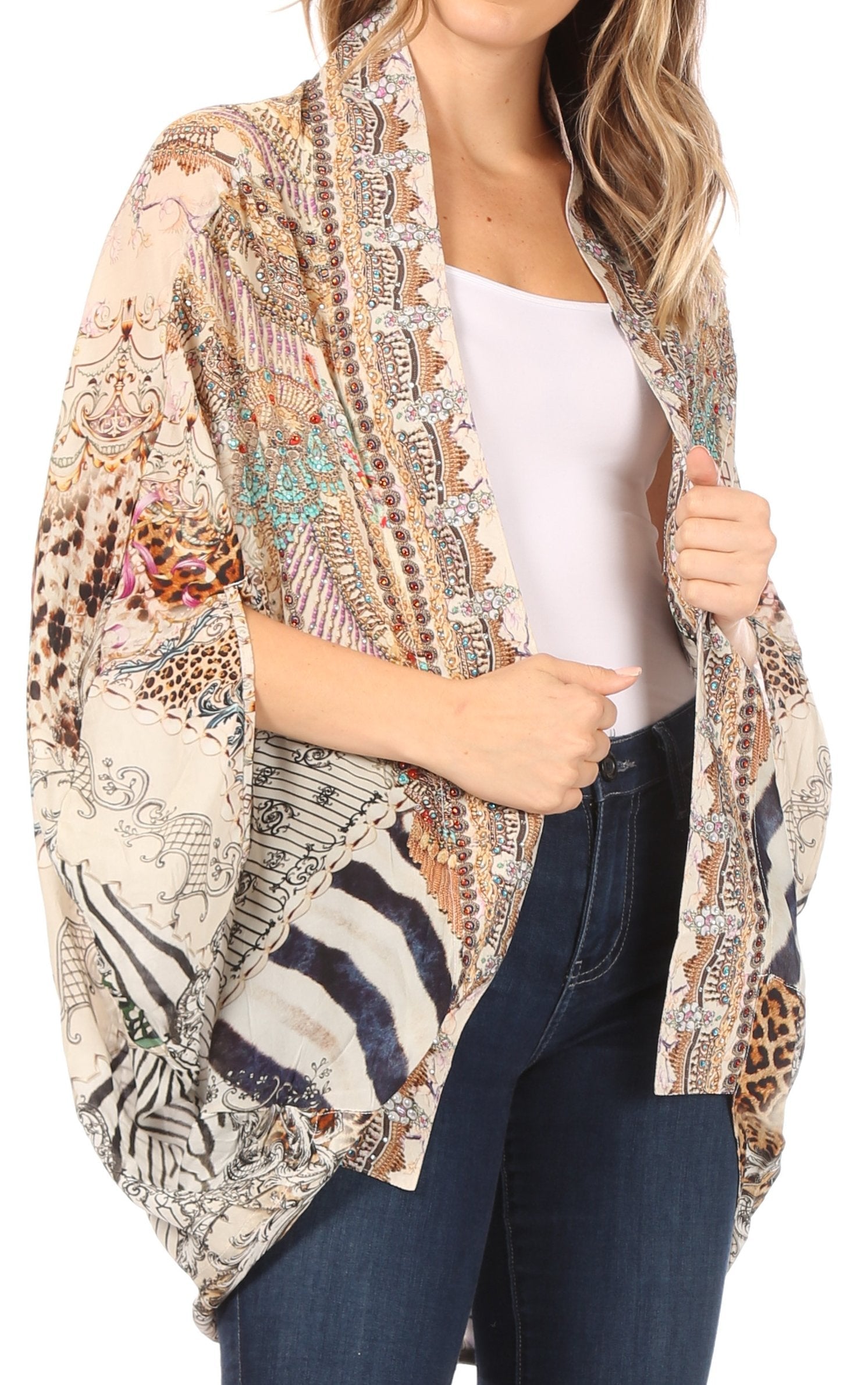 Woman wearing a patterned kimono-style jacket over a white top and blue jeans on a white background