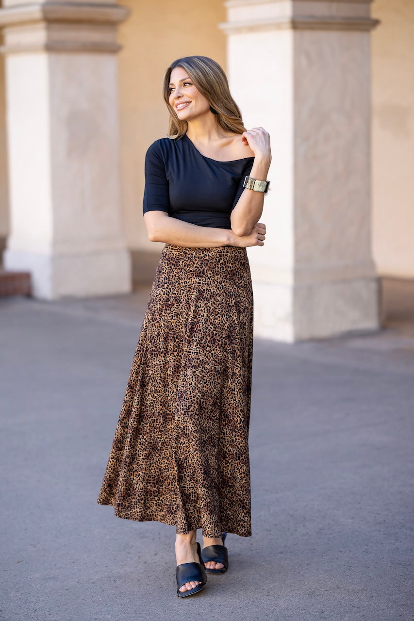 Woman wearing a black top and patterned skirt standing in front of classical architecture.