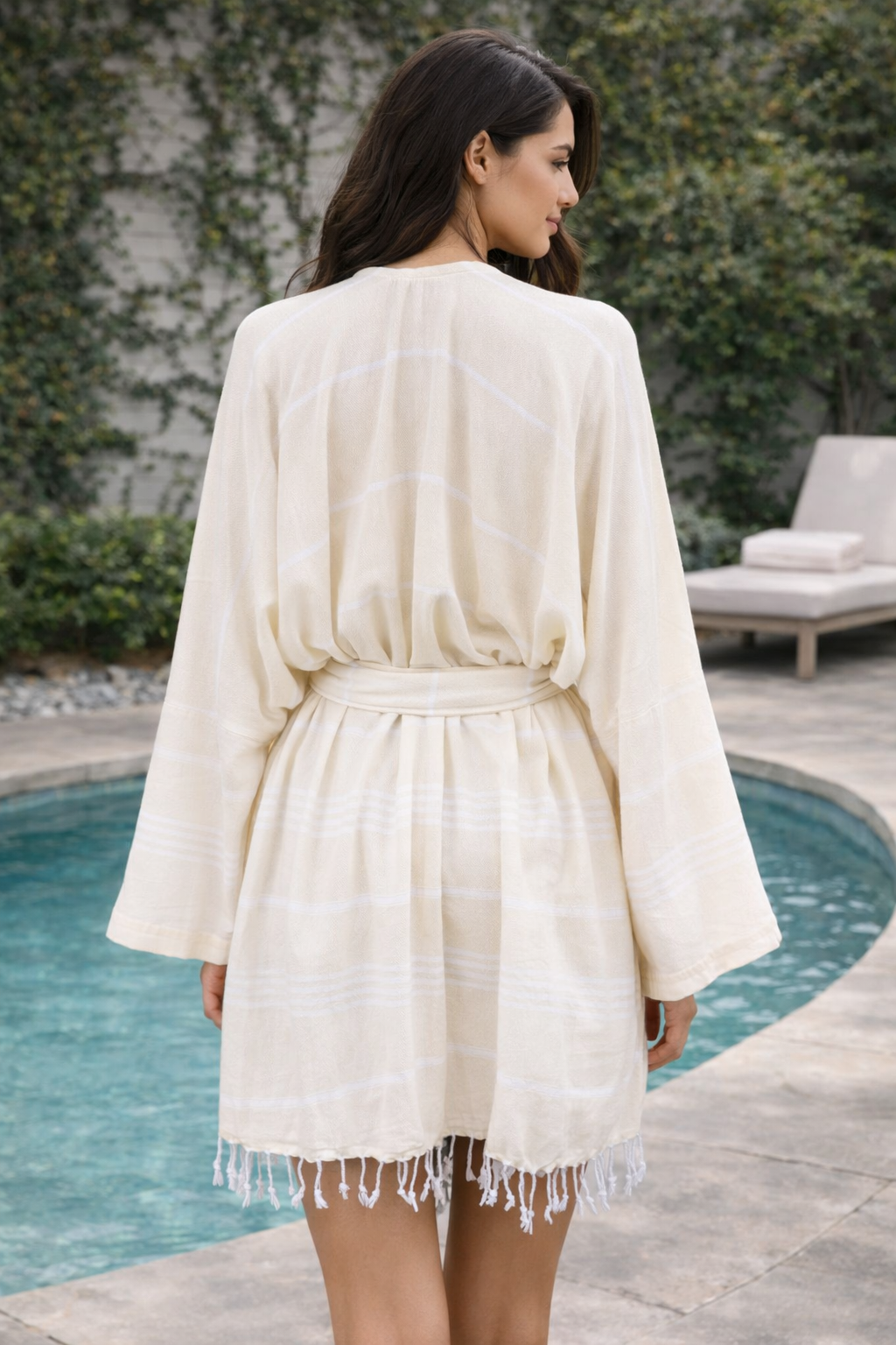 Woman wearing a white robe by a poolside