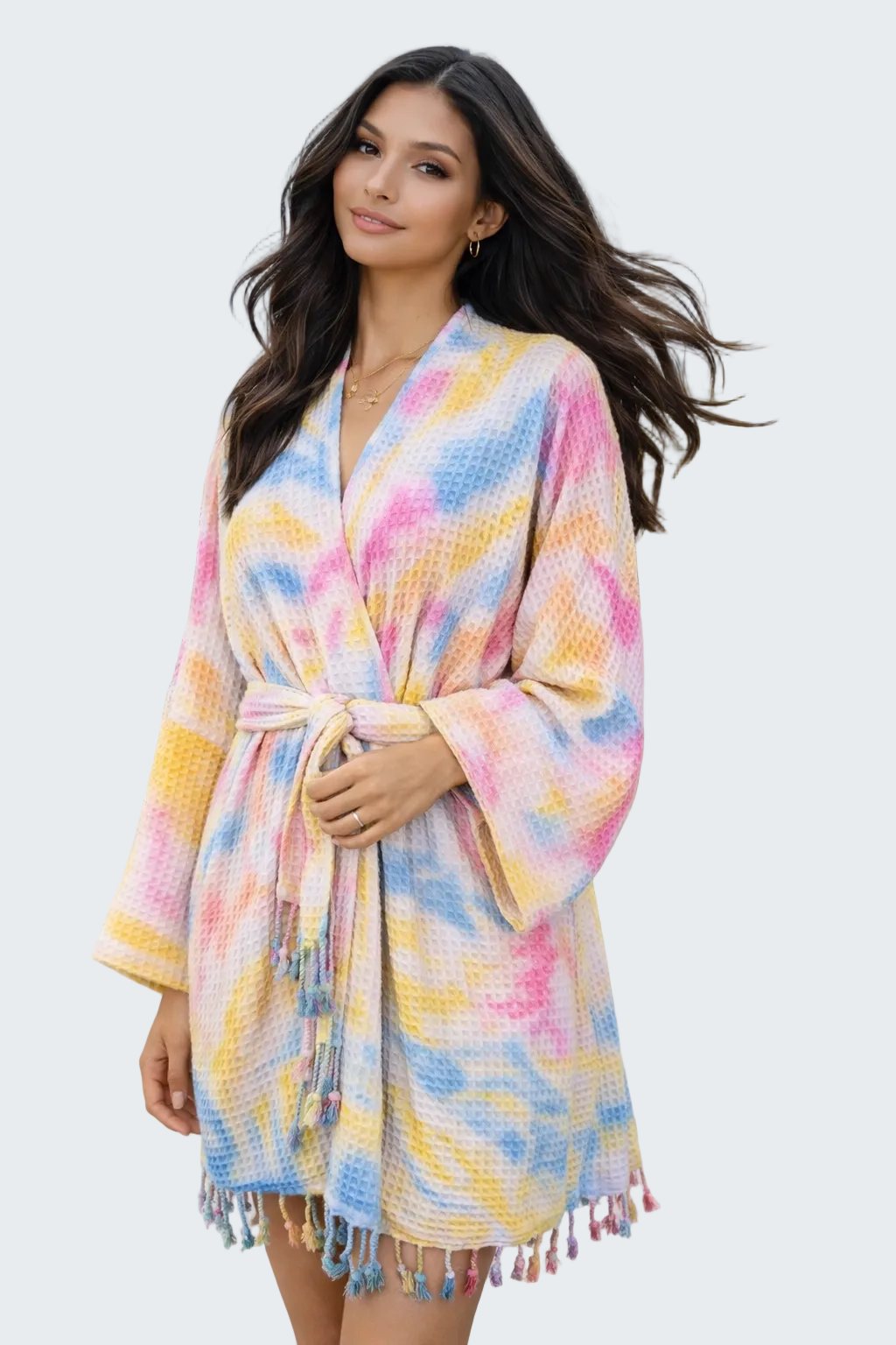 Woman wearing a colorful robe on a beach with ocean and house in the background