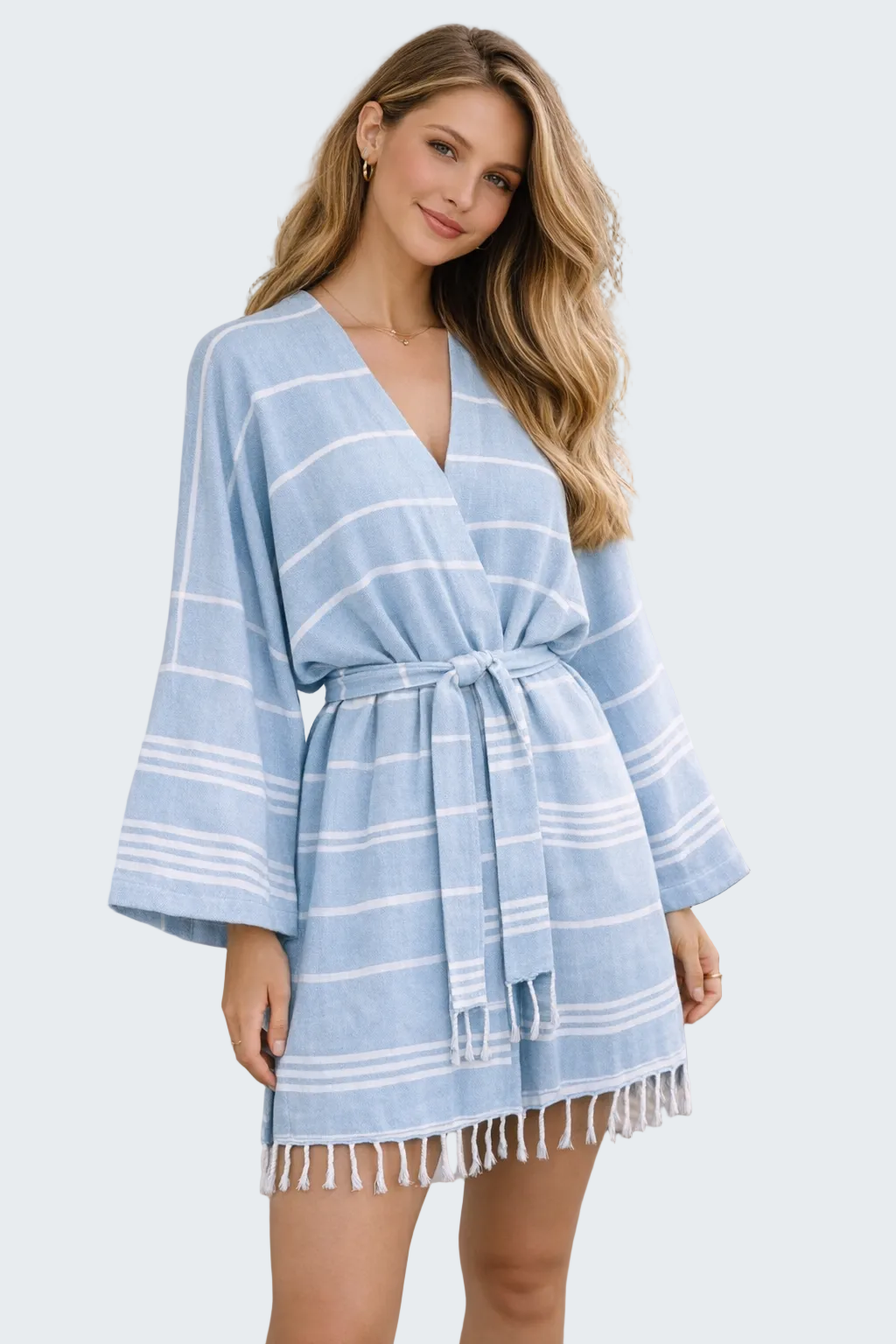 Woman wearing a blue striped dress with fringe details outdoors.