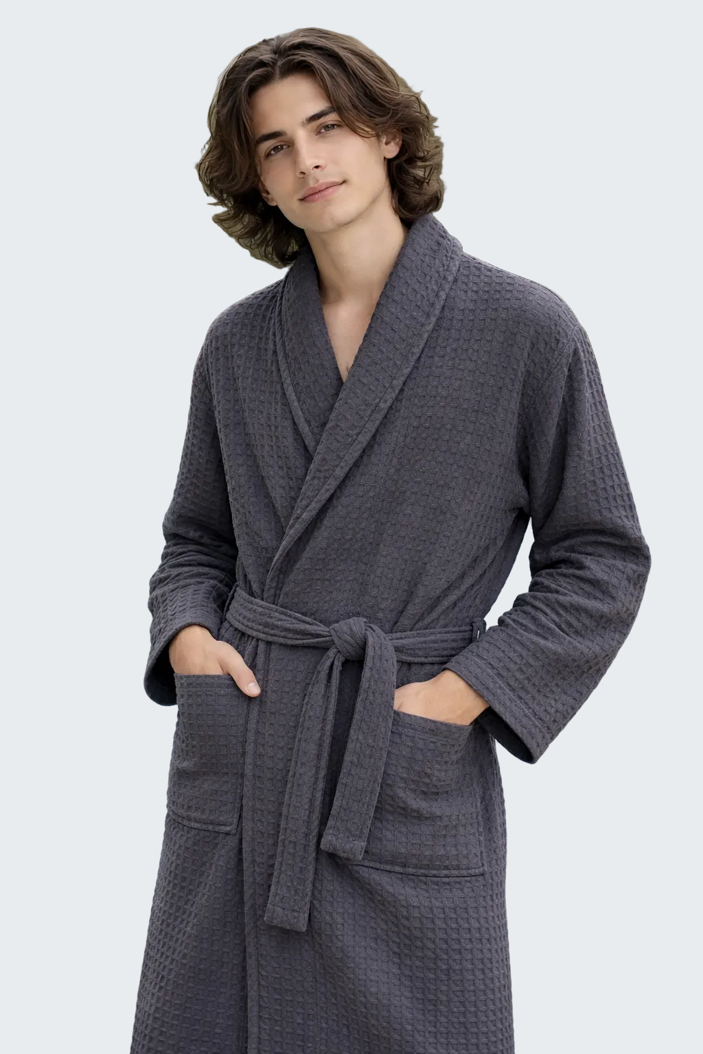 Man wearing a gray robe by a pool with palm trees in the background