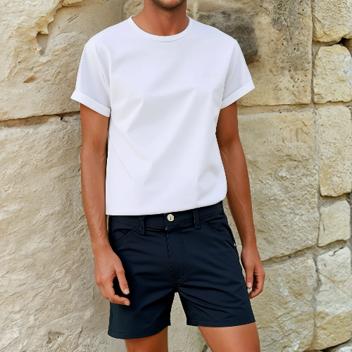 Person wearing a white t-shirt and navy shorts against a stone wall.