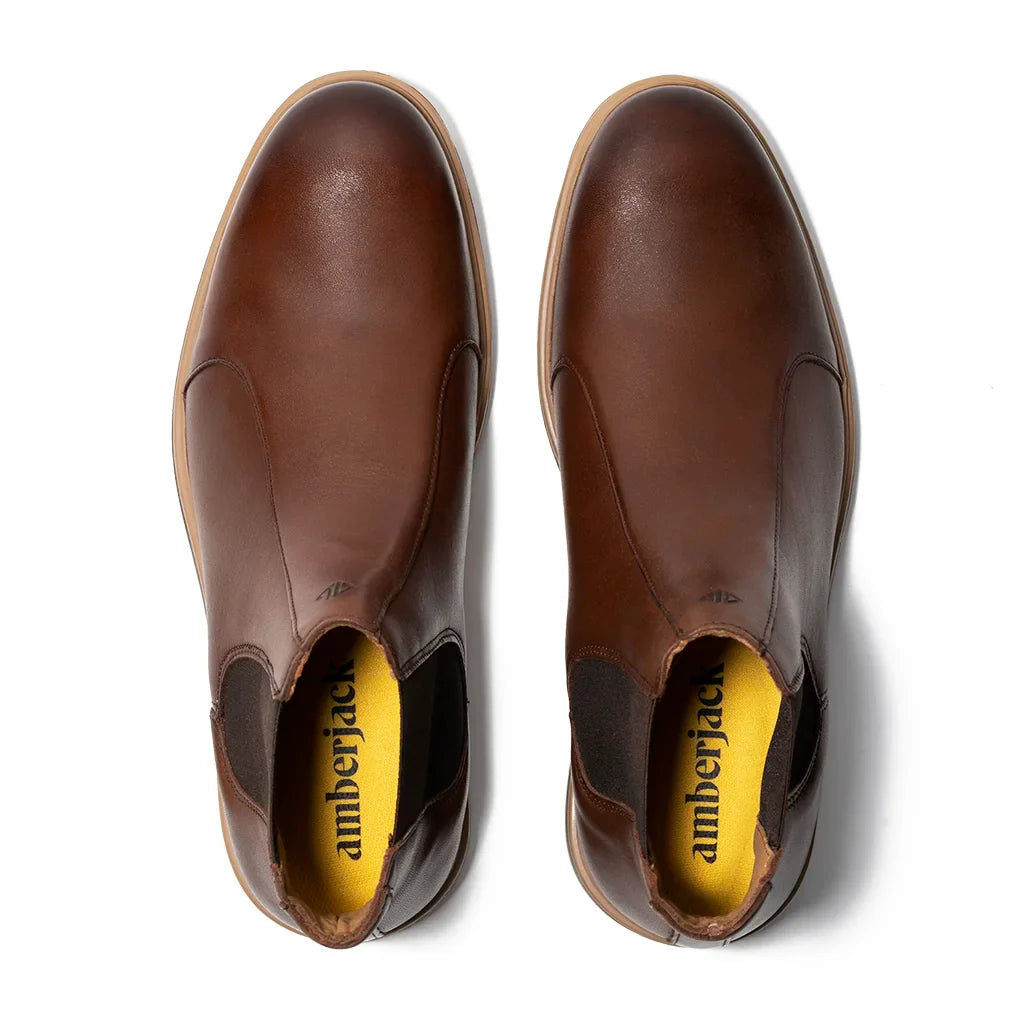 Pair of brown leather shoes with yellow interior on a white background