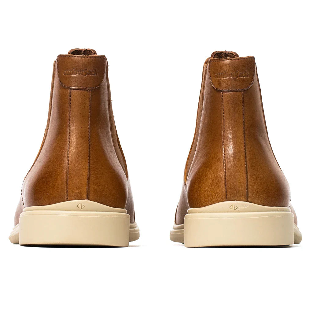 Pair of brown leather boots with white soles on a white background