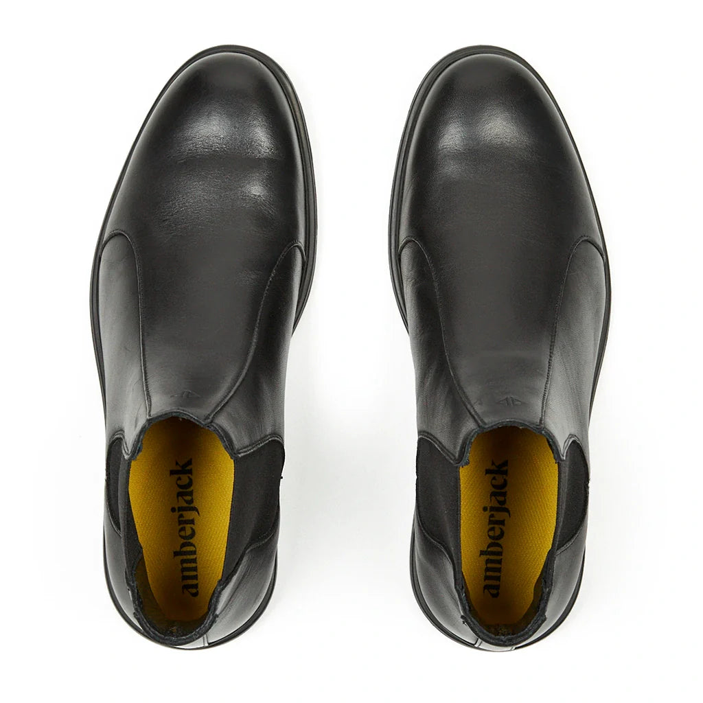 Black leather boots with yellow lining on a white background