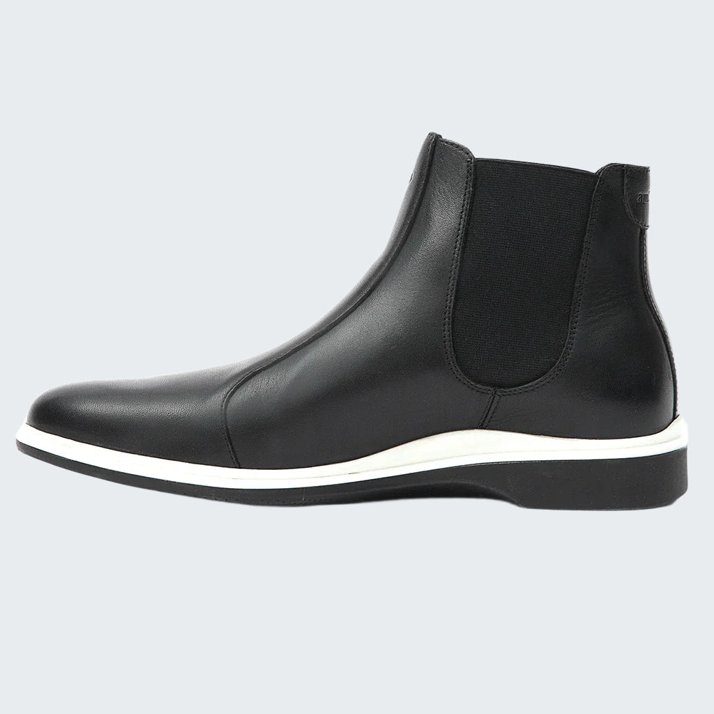 Black Chelsea boot with a white sole on a white background