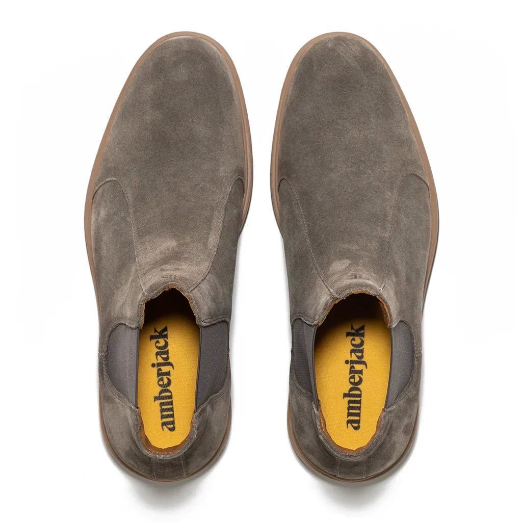 Pair of gray suede shoes with yellow interior on a white background