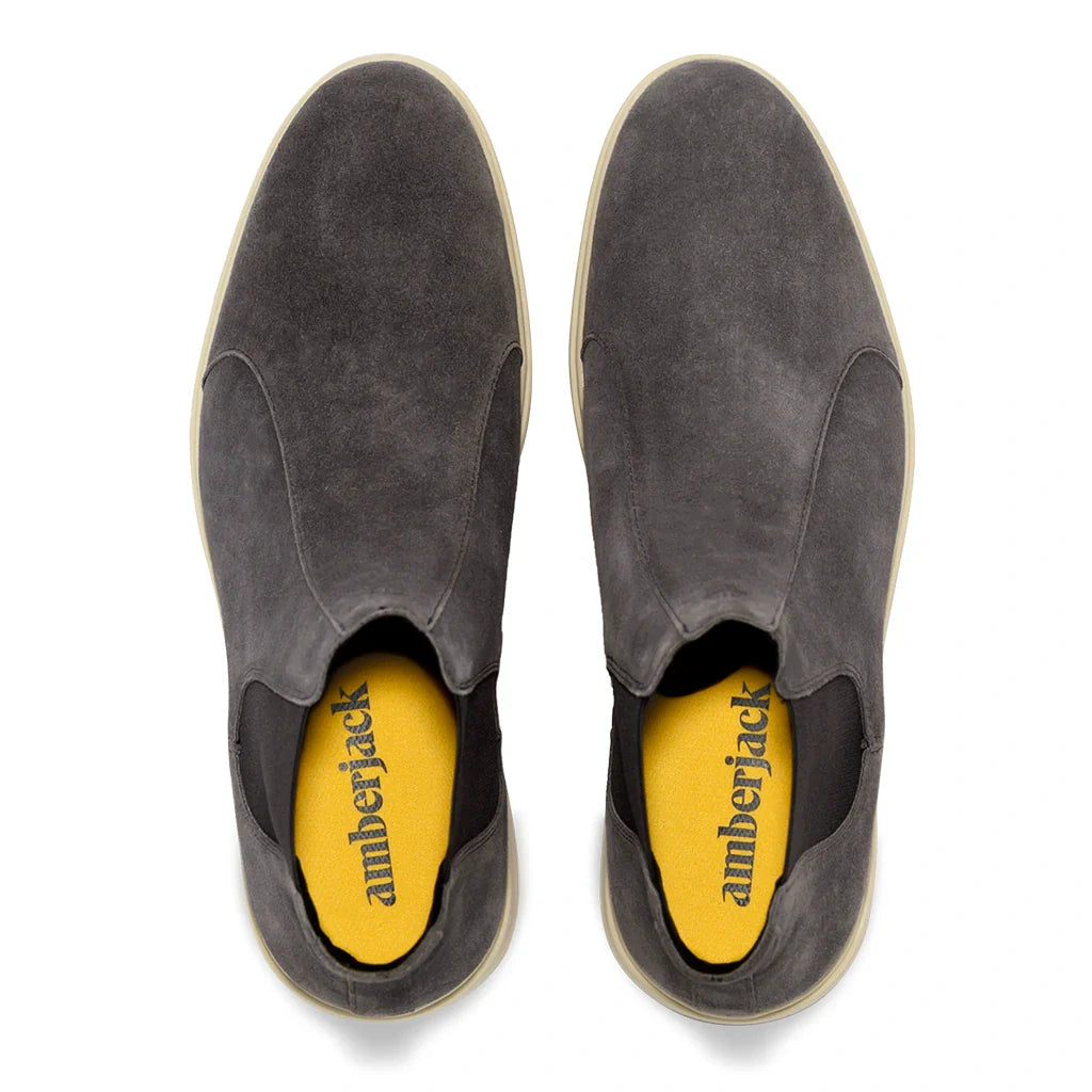 Pair of gray slip-on shoes with yellow soles on a white background