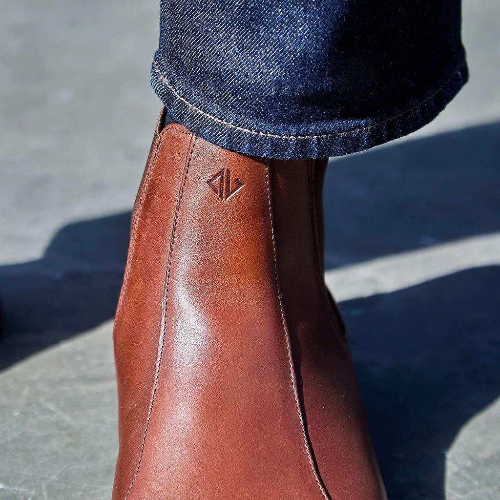 Brown leather boot with a brand logo on a concrete surface