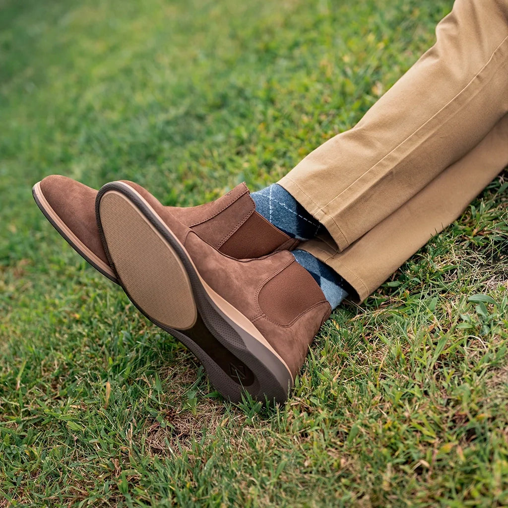 Brown leather shoes on a person's feet with grass in the background