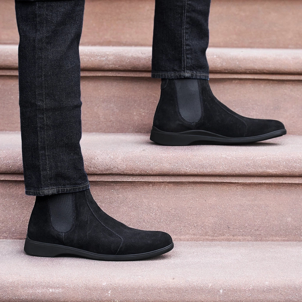 Black suede Chelsea boots worn on beige steps