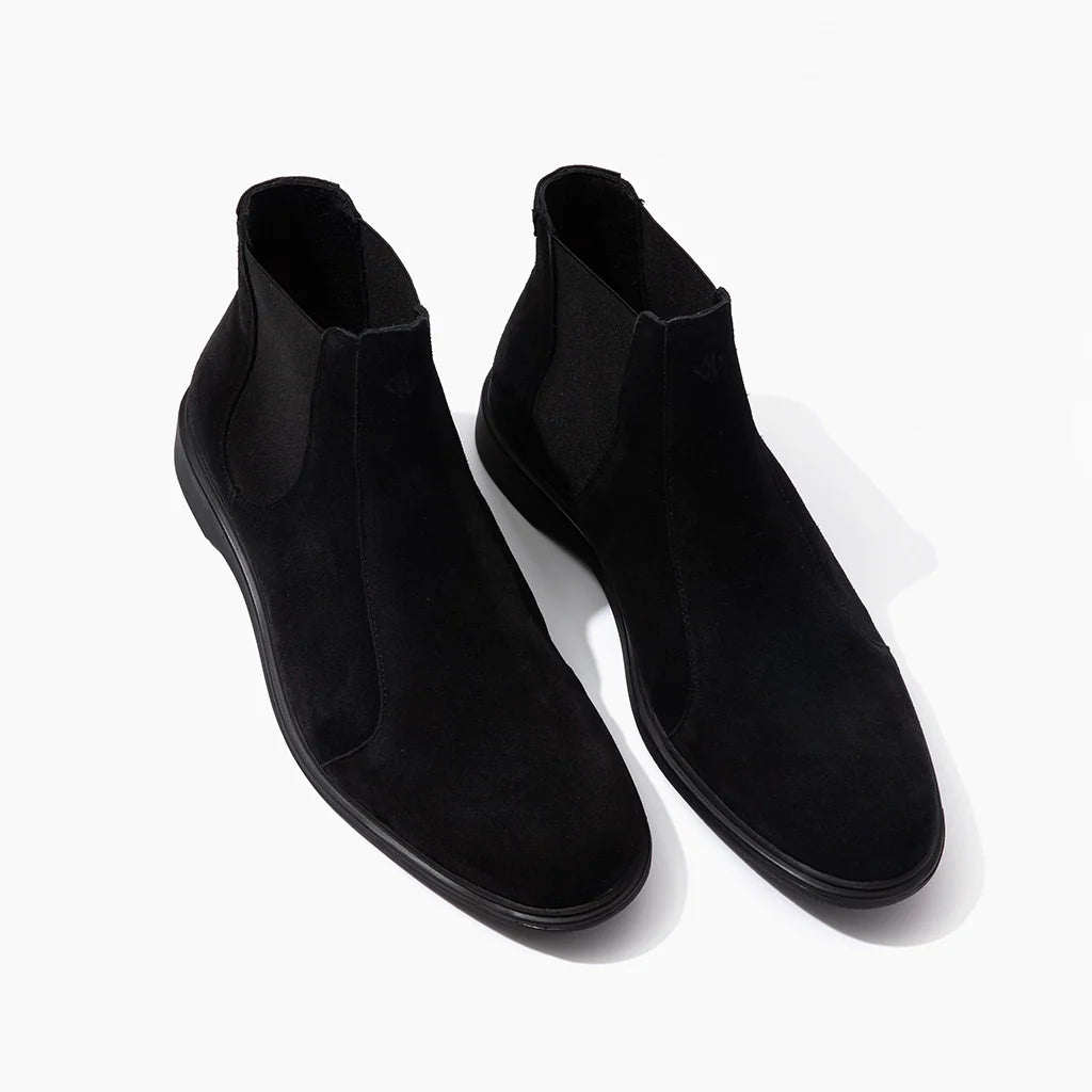 Pair of black suede ankle boots on a white background