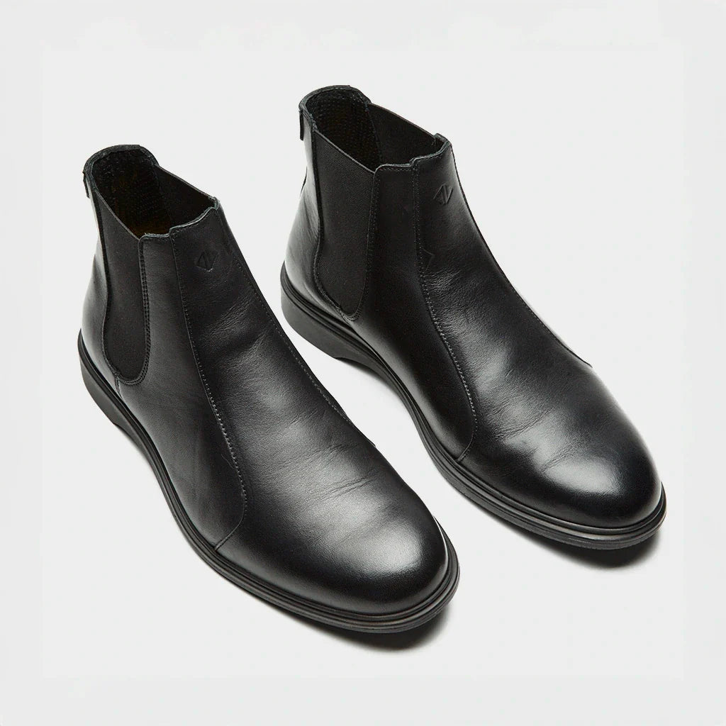 Pair of black leather Chelsea boots on a light gray background