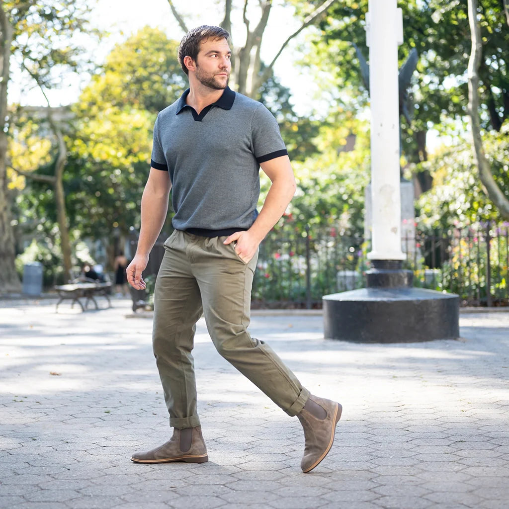 Man walking outdoors in a park-like setting wearing a gray polo shirt and olive green pants.