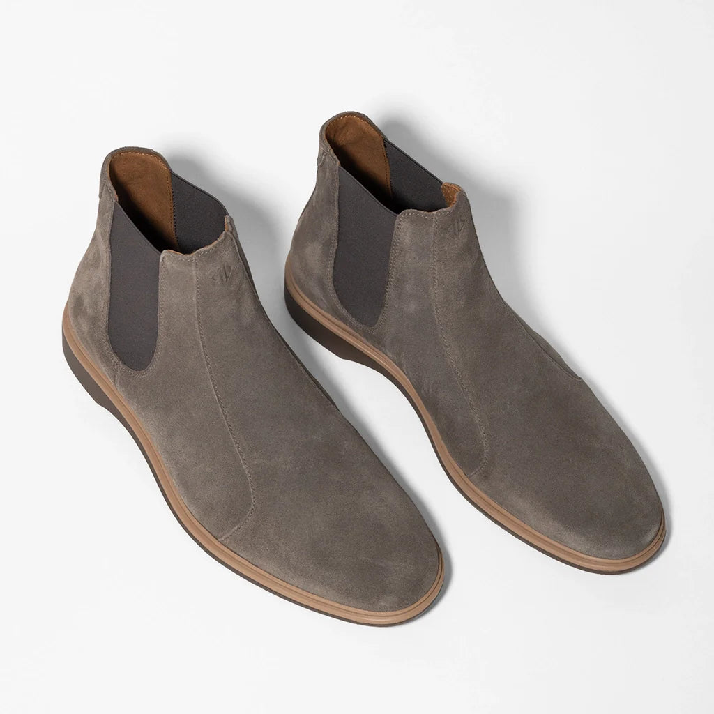 Pair of brown suede Chelsea boots on a light gray background